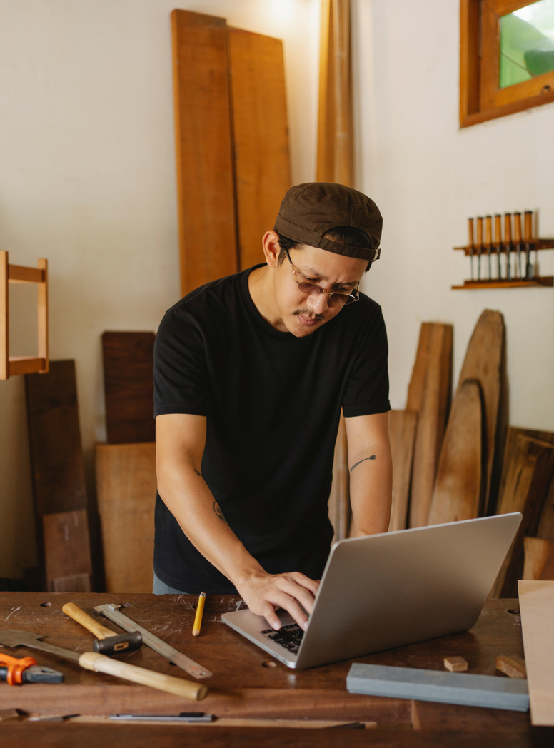 Pensive artisan using laptop in creative workshop studio