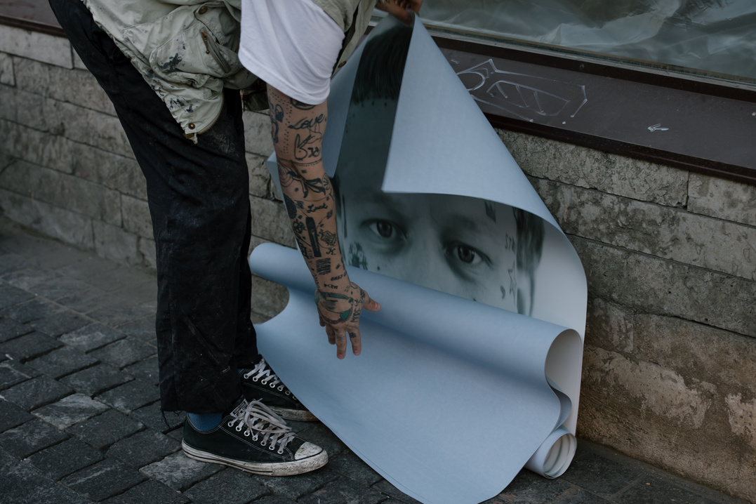 Person with Arm Tattooes holding a Poster 